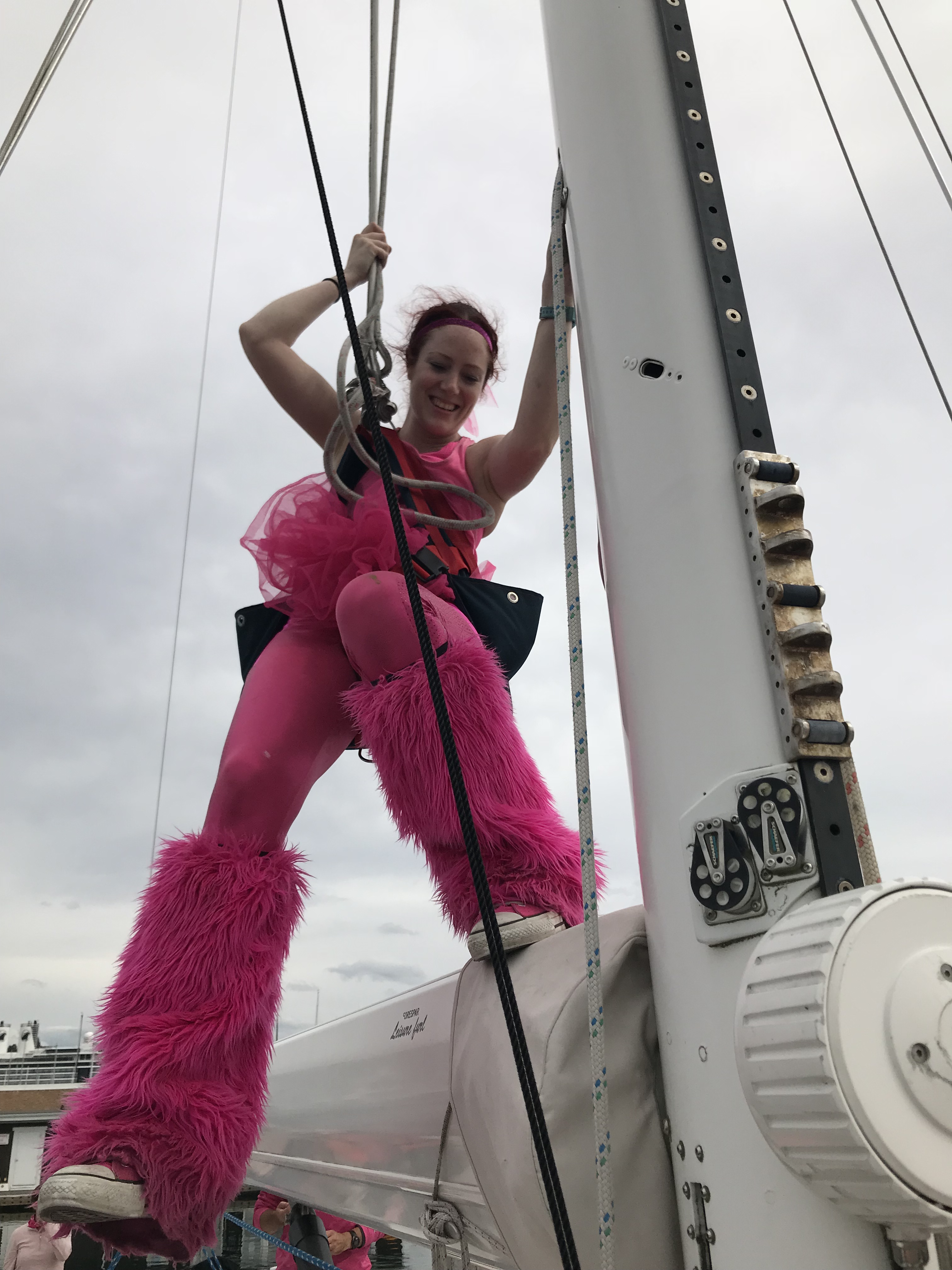 Happy woman in an all pink outfit in mast-climbing gear standing on a boom.